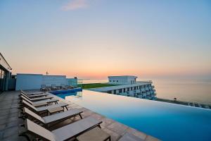 a hotel swimming pool with chairs and the ocean at Infinity by Sea Apartment Beach Resort - parking in Mamaia