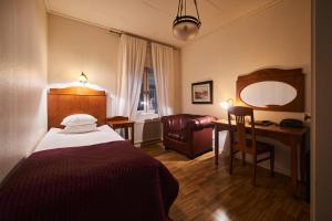 a bedroom with a bed and a desk and a chair at Hotell Läckö in Lidköping