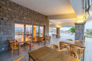un restaurante con mesas y sillas y una pared de piedra en Cinarli Kasri en Gokceada Town