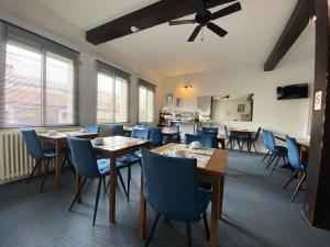 Hotel le Pasteur في رويان: غرفة طعام مع طاولات خشبية وكراسي زرقاء