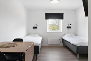 Cette chambre comprend 2 lits, une table et une fenêtre. dans l'établissement First Camp Mölle-Höganäs, à Mölle
