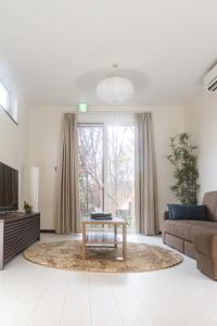 a living room with a coffee table in front of a window at Audrey Chalet in Niseko