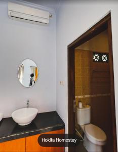 a bathroom with a sink and a toilet and a mirror at Hokita Home Stay in Nusa Lembongan