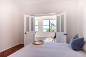 a white bedroom with a large bed with a window at Daydream - 150m from the beach in Shellharbour