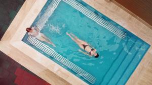 zwei Personen schwimmen in einem Pool in der Unterkunft Hotel Sapphire Bakuriani in Bakuriani