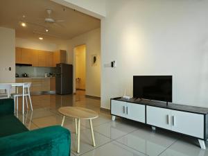 ein Wohnzimmer mit einem Sofa, einem TV und einem Tisch in der Unterkunft Metropol Serviced Apartment - Bukit Mertajam in Bukit Mertajam