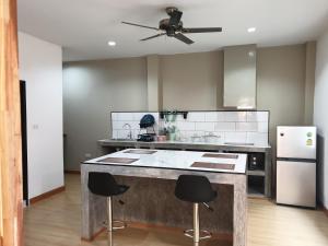 a kitchen with a large island with two bar stools at My Friend's House Villa in Ban Karon