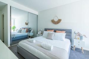 een slaapkamer met een groot wit bed en een spiegel bij Surf Beach Retreat - 100m from the beach in Kiama