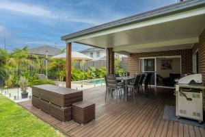 a deck with a table and chairs and an umbrella at Sea Change in Shellharbour