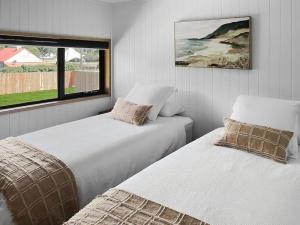 two white beds in a room with a window at Pod on the Park in Kiama