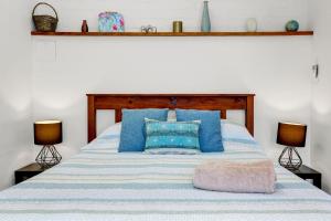 sypialnia z łóżkiem z niebieskimi poduszkami i 2 lampami w obiekcie Minnamurra Retreat 1 w mieście Minnamurra