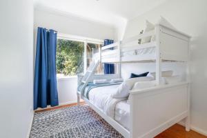 a white bedroom with a white bunk bed and a window at The Farmer s Retreat in Kiama