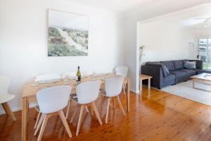 a dining room and living room with a wooden table and white chairs at The Farmer s Retreat in Kiama