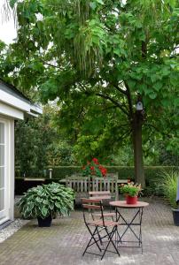 eine Terrasse mit einem Tisch und einer Bank mit Blumen in der Unterkunft B&B De Rozenhorst in Baarlo