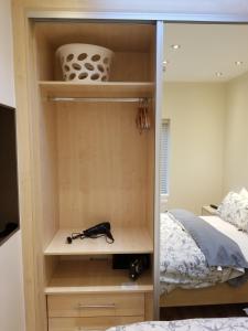 London Luxury Apartment 4 Bedroom Sleeps 12 people with 4 Bathrooms 1 Min walk from Station في Wanstead: غرفة نوم مع خزانة مع سرير ومرآة