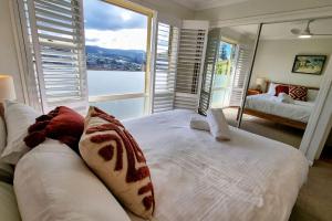 a bedroom with a white bed and a large window at Blue Skies Beach House in Gerringong