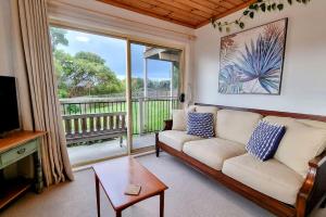 a living room with a couch and a large window at Blue Skies Beach House in Gerringong