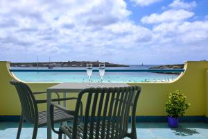 a table with two wine glasses on a balcony with a beach at Hotel Baia Turchese in Lampedusa