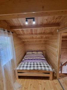 uma cama num quarto de madeira com piso de madeira em Domek letniskowy piętrowy na Kaszubach jezioro Ostrów Mausz em Kłodno
