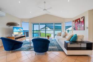 Una sala de estar con un sofá blanco y sillas azules. en EastsHaven, en Kiama