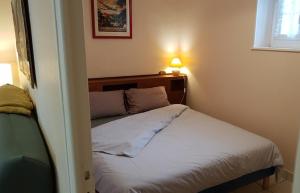 um pequeno quarto com uma cama com lençóis brancos em Gîte de Champdoré em Nanthiat