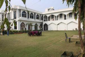 a large white building with tables and chairs in a yard at The Hotel Raj Palace in Bharatpur