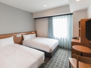 um quarto de hotel com duas camas e uma janela em Sotetsu Fresa Inn Kobe Sannomiya em Kobe