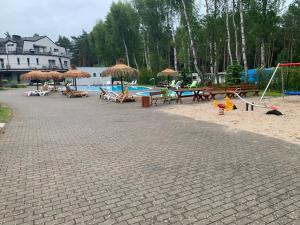 a playground with tables and umbrellas and a pool at Apartament na Leśnej in Pobierowo