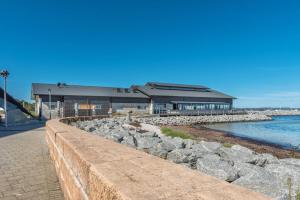 a building with a stone wall next to the water at Foreshore Apartment 104 in Albany