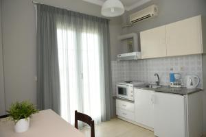 a kitchen with white cabinets and a table and a window at Skalidis Apartments in Tolo