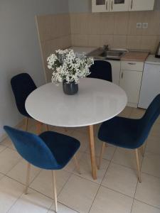una mesa blanca con sillas azules y un jarrón de flores en Apartments Tatjana en Jagodina