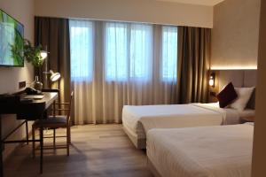a hotel room with two beds and a desk at The Brunei Hotel in Bandar Seri Begawan
