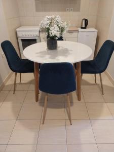 una mesa blanca con sillas azules y un jarrón de flores en Apartments Tatjana en Jagodina
