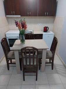 una cocina con una mesa con sillas y un jarrón de flores en Apartments Tatjana en Jagodina