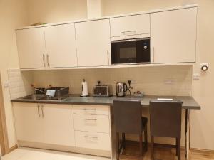 a kitchen with white cabinets and a table with chairs at London Luxury Apartments 3 Bedroom Sleeps 8 with 3 Bathrooms 4 mins walk to tube free parking in Ilford