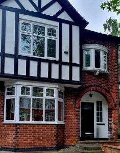 a red brick house with a black and white building at Mapperley Park Guesthouse in Nottingham