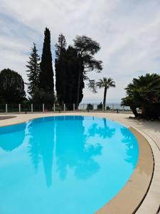 uma grande piscina azul com árvores ao fundo em « La Grande Résidence » Vue Mer, Piscine em Menton