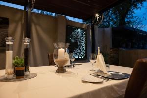 einen Tisch mit einem weißen Tischtuch und einer Kerze darauf in der Unterkunft Chobe River Lodge in Kasane