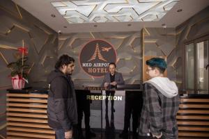 Arnavutköy的住宿－MED Airport Hotel，三人站在旅馆房间的讲台上