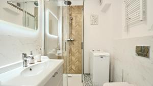 a white bathroom with a sink and a shower at Apartamenty Sun & Snow Półwysep Dziwnów in Dziwnów