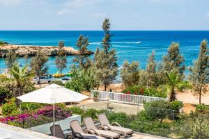 a view of the beach from a resort with chairs and an umbrella at Beach Front Aqua Marina by Ezoria Villas in Paralimni +36 photos