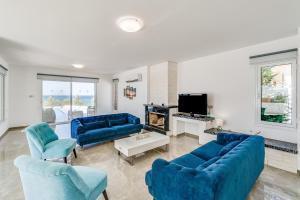 een woonkamer met blauwe banken en een tv bij Beach Front Aqua Marina by Ezoria Villas in Paralimni