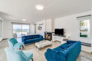 uma sala de estar com sofás azuis e uma televisão em Beach Front Aqua Marina by Ezoria Villas em Paralimni