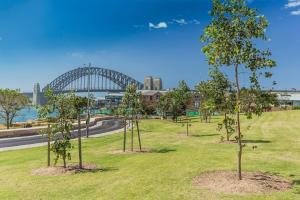 a park with trees and a bridge in the background at Beautiful 2-Bed Apartment with ocean views of Barangaroo in Sydney