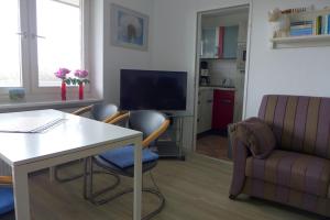 Una sala de estar con una mesa y sillas y un televisor. en Tief 10 Meerblick mit Internet 304, en Wangerland