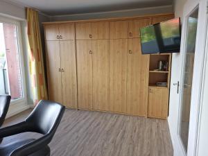 uma sala de estar com armários de madeira e uma televisão de ecrã plano em Tief 10 Wattwurm em Wangerland