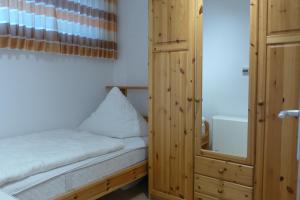 Kleines Zimmer mit einem Bett und einem Holzschrank. in der Unterkunft Tief 12 Strandkieker mit Internet und Strandkorb 54 in Wangerland