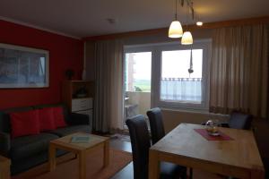 a living room with a table and a living room with a couch at Tief 10 Steuerbord 502 in Wangerland