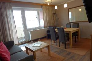 a living room with a dining room table and chairs at Tief 10 Steuerbord 502 in Wangerland