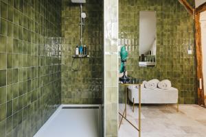La salle de bains est pourvue d'une baignoire et d'une douche avec du carrelage vert. dans l'établissement Les Callots - Maison d'hôtes, à Champignelles